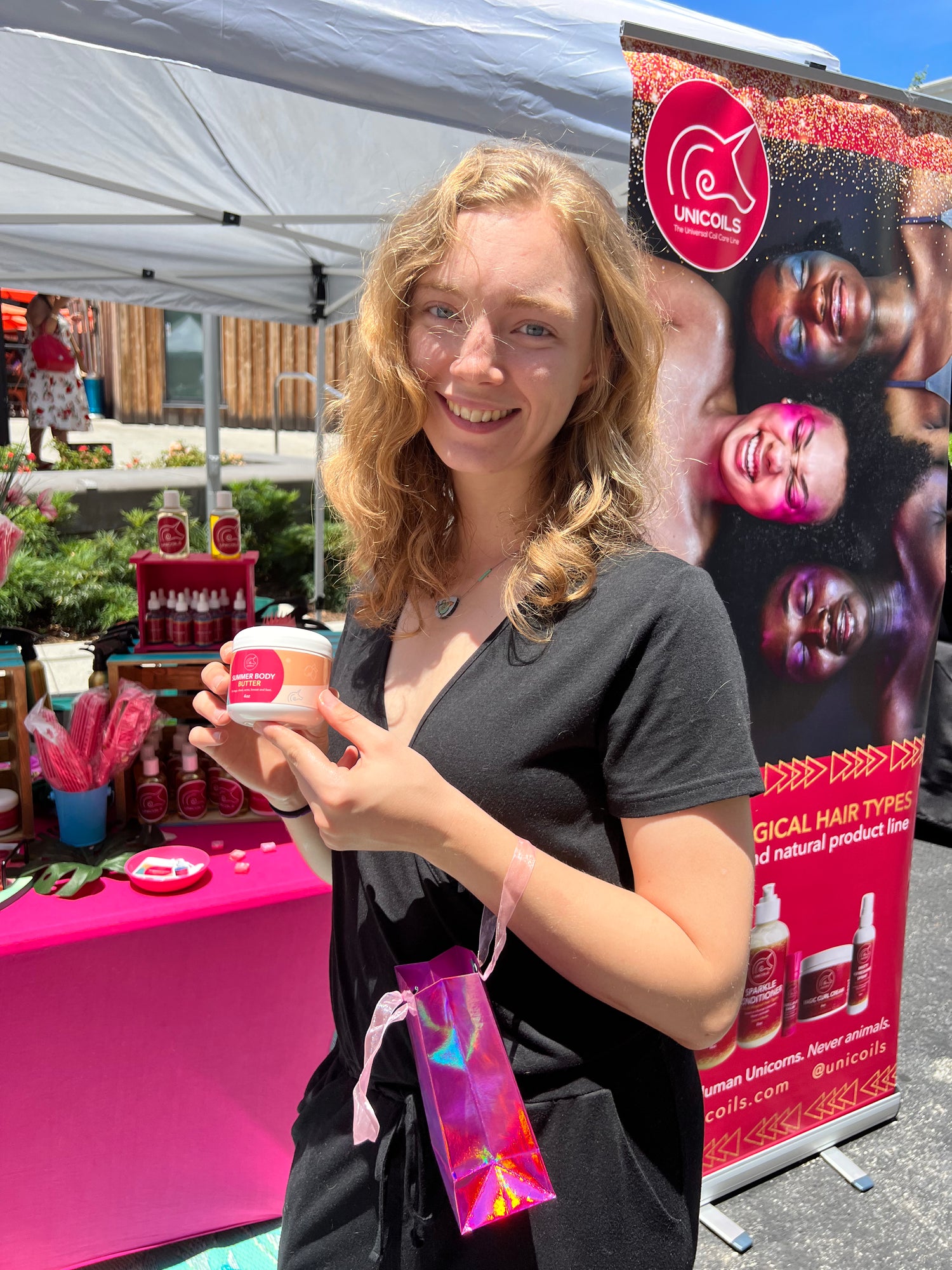 Woman holding unicoils container at an outdoor event with a unicoils backdrop in atlanta .