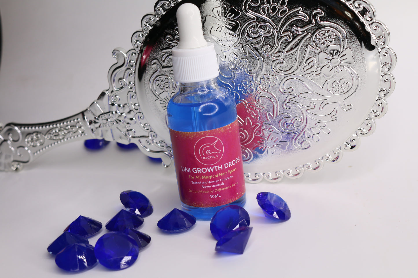 Bottle of 'Life Growth Drops' with blue capsules on a decorative silver tray.